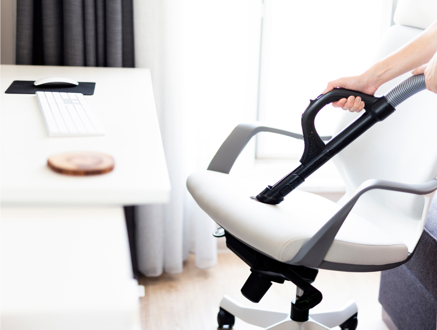 a person is cleaning an office chair with a vacuum cleaner .